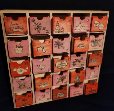 Festive advent cabinet - Colourful design idea. 

Measurements:
Outer: 35.5cm x 35.5cm
Each Drawer: 4.5cm x 5.5cm x 4cm